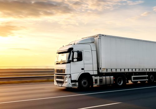 white-semi-truck-driving-highway-sunset